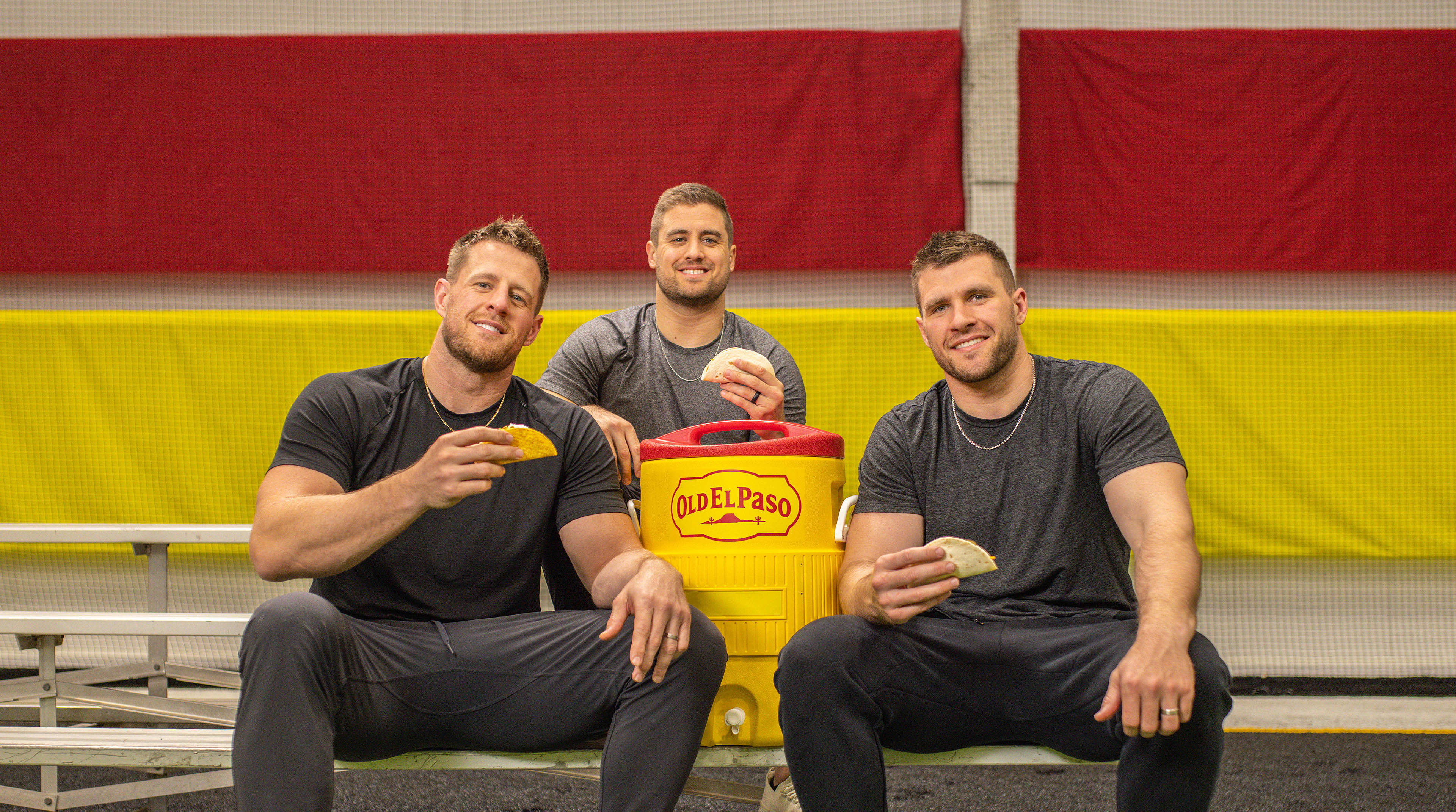 Watts Brothers in a training room, sitting on bleachers, eating tacos